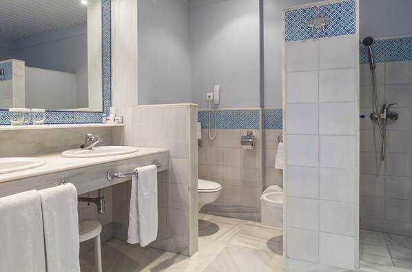 A modern bathroom with two sinks, a toilet, and a shower.