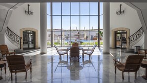 A spacious lobby with a large glass wall, wooden furniture, and a pool view. - Hotel Duque De Najera (Rota)