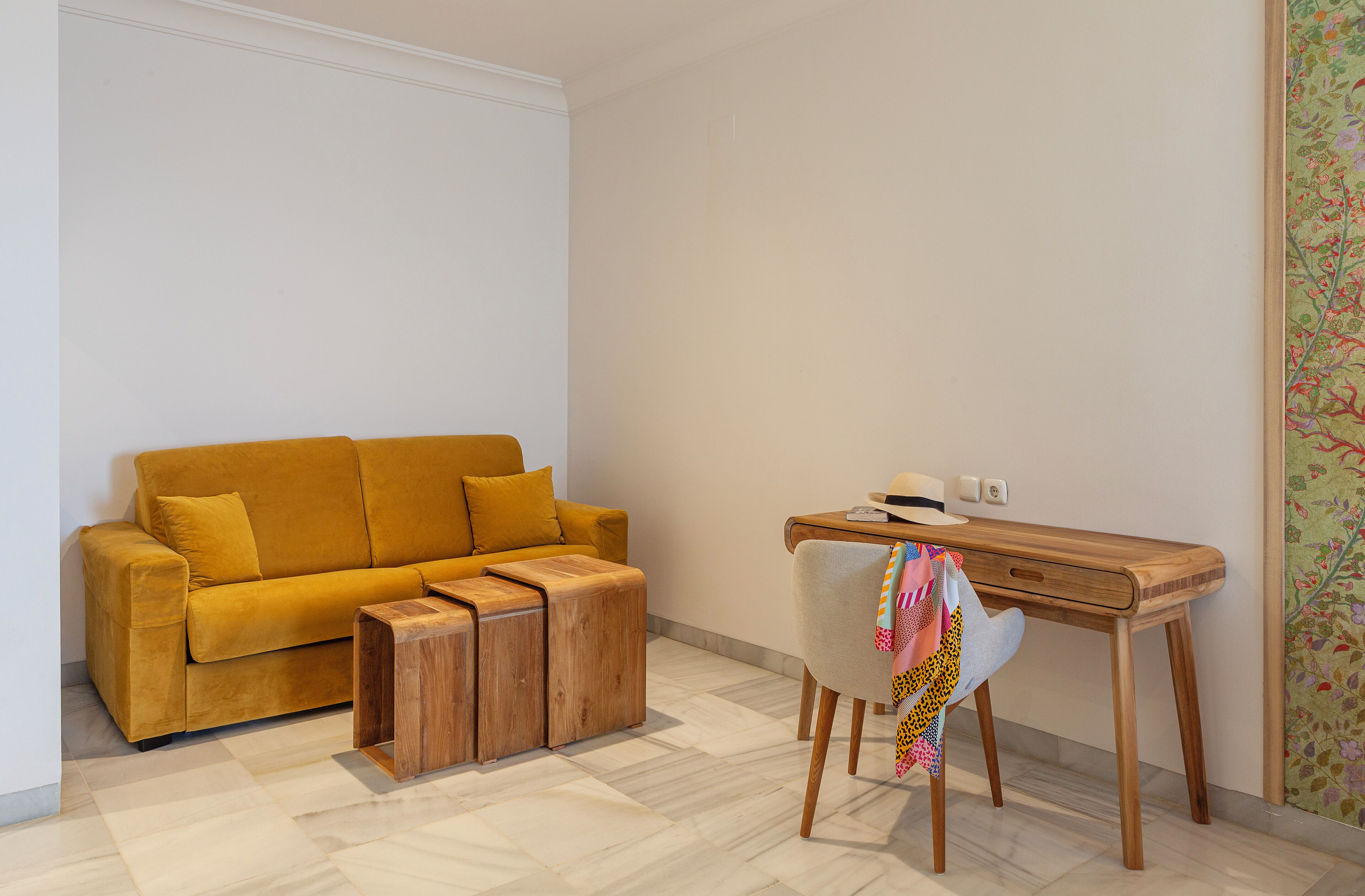 Ein modernes Wohnzimmer mit einem senffarbenen Sofa, einem Holztisch und einem Schreibtisch mit Stuhl.