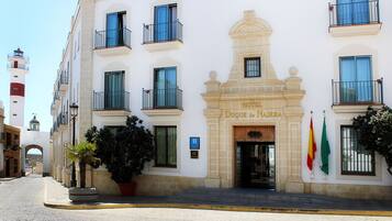 Fachada de hotel com entrada destacada, varandas e bandeiras.