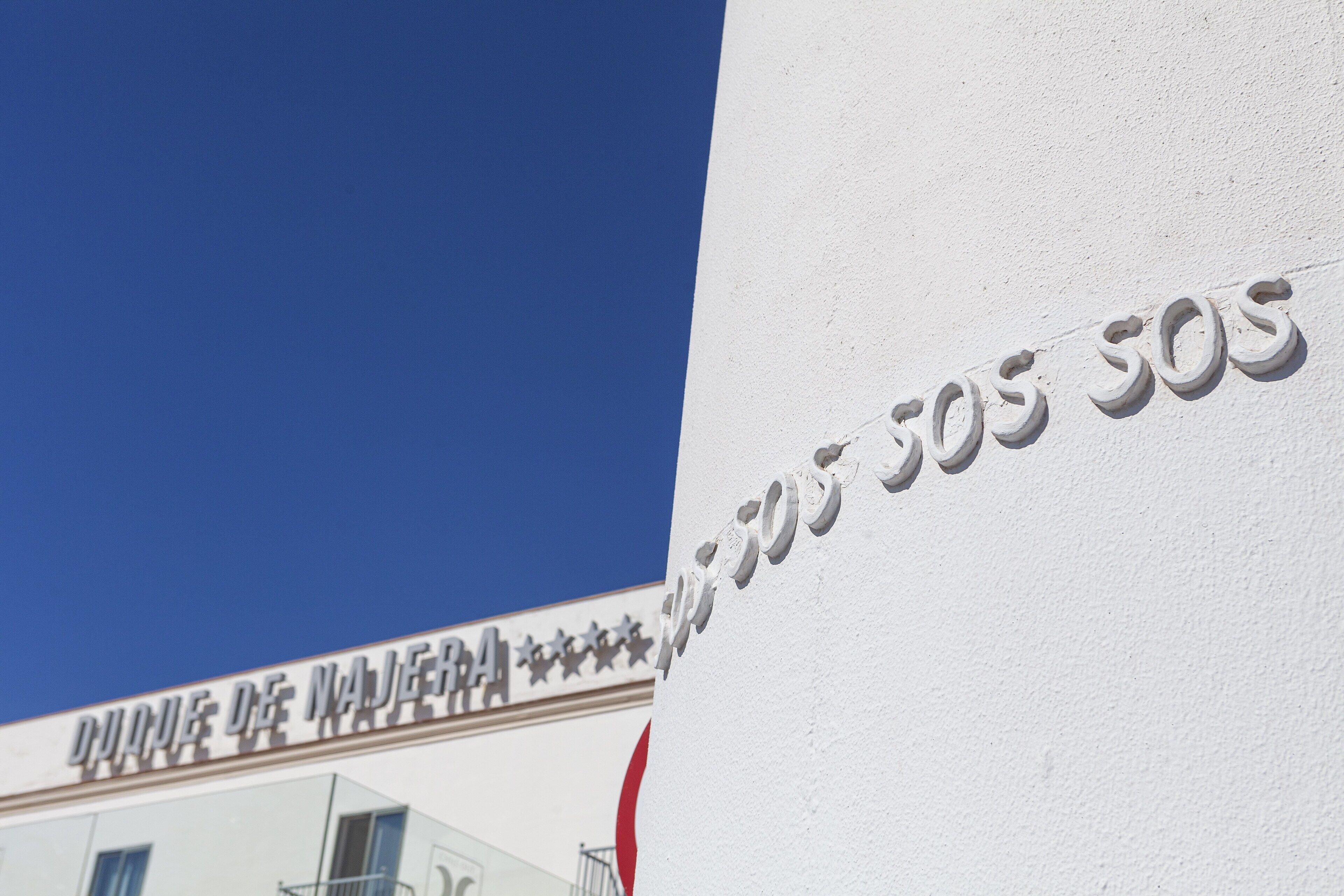 Un edificio con un cartel que dice "DURANTE DE NAJERA" y una serie de números "SOS SOS SOS" en una pared blanca.