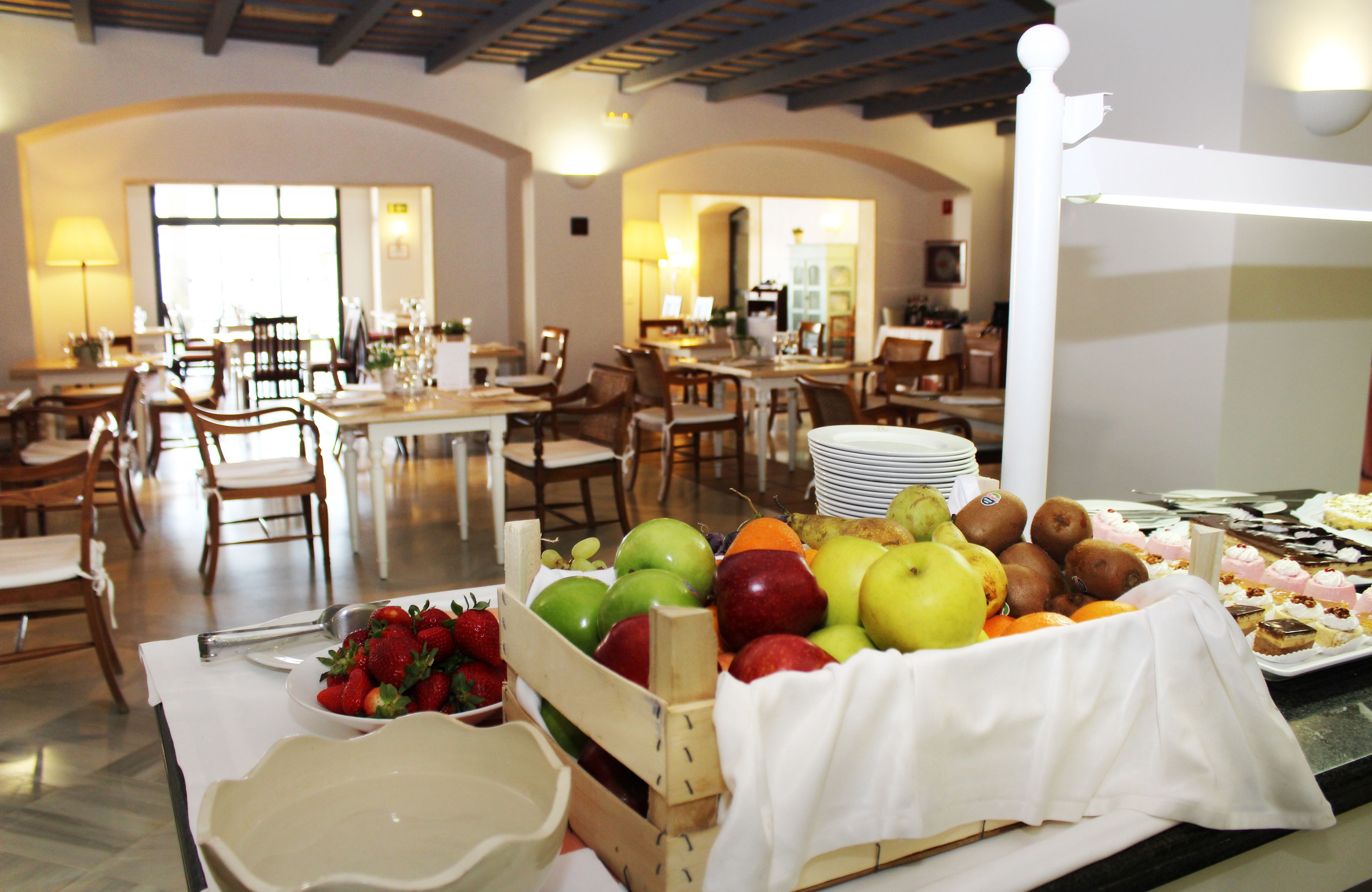 A dining area with tables, chairs, and a fruit display.