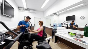 A modern fitness center with cardio equipment, a reception desk, and a water dispenser.