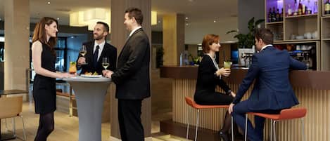 A modern bar area with a bar counter, stools, and a well-stocked shelf with bottles.