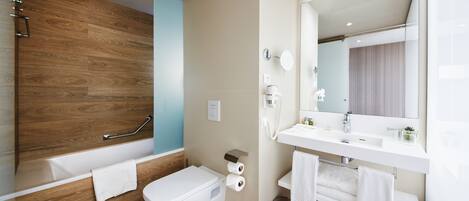 A modern bathroom with a wooden vanity, a bathtub, a toilet, and a mirror.