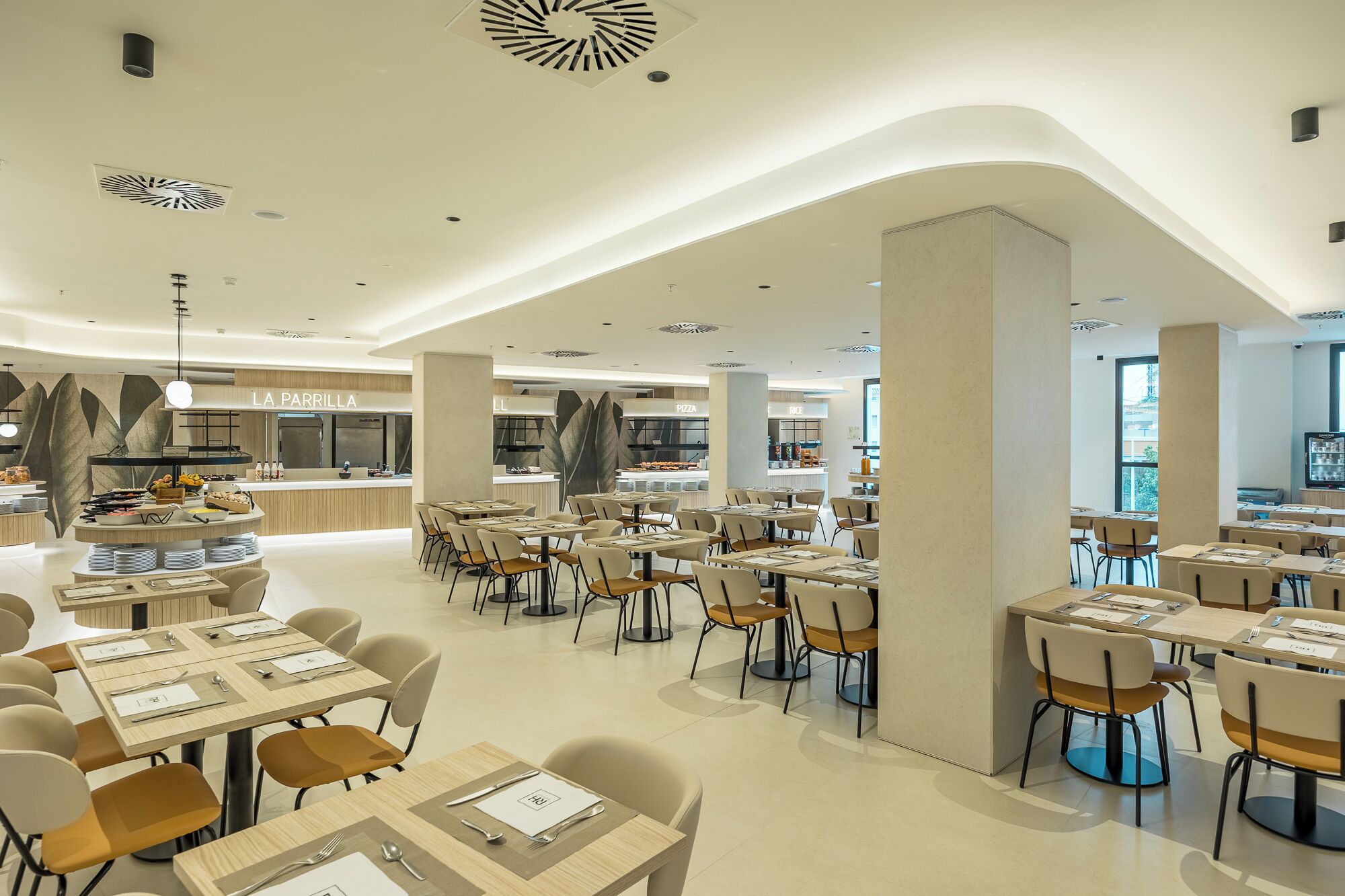 A spacious restaurant with multiple dining areas, a pizza station, and a coffee bar.