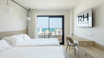 Habitación de hotel con una cama, un escritorio, una silla y vista al mar.