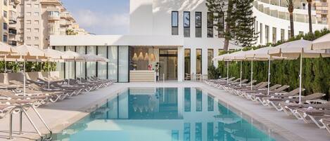 Una piscina techada, una piscina al aire libre, sombrillas