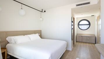 Un dormitorio moderno con una cama grande, un ventanal redondo y un banco empotrado.
