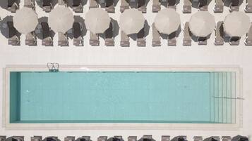 A pool with multiple umbrellas and lounge chairs arranged around it.
