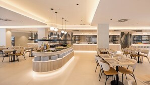 Un restaurante moderno con una barra central, varias mesas de comedor y una cocina al fondo.