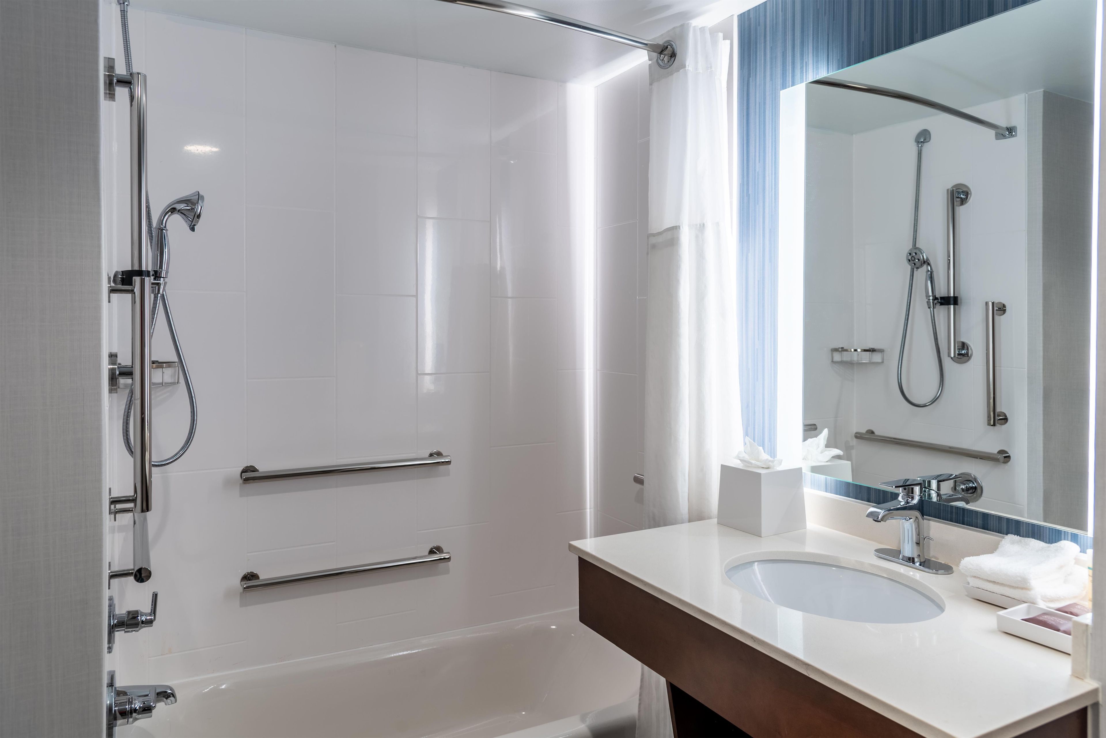 Un baño moderno con cabina de ducha a ras de suelo, tocador con lavabo y un espejo grande.