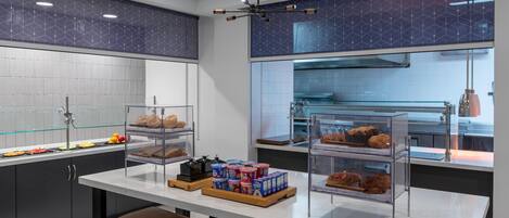 Una cocina moderna con encimera de mármol, vitrinas de vidrio y una zona de estar con taburetes.