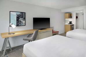 A hotel room with a bed, a desk with a computer, a TV, a chair, and a kitchenette. - Hilton Garden Inn Arlington/Courthouse Plaza (Arlington)