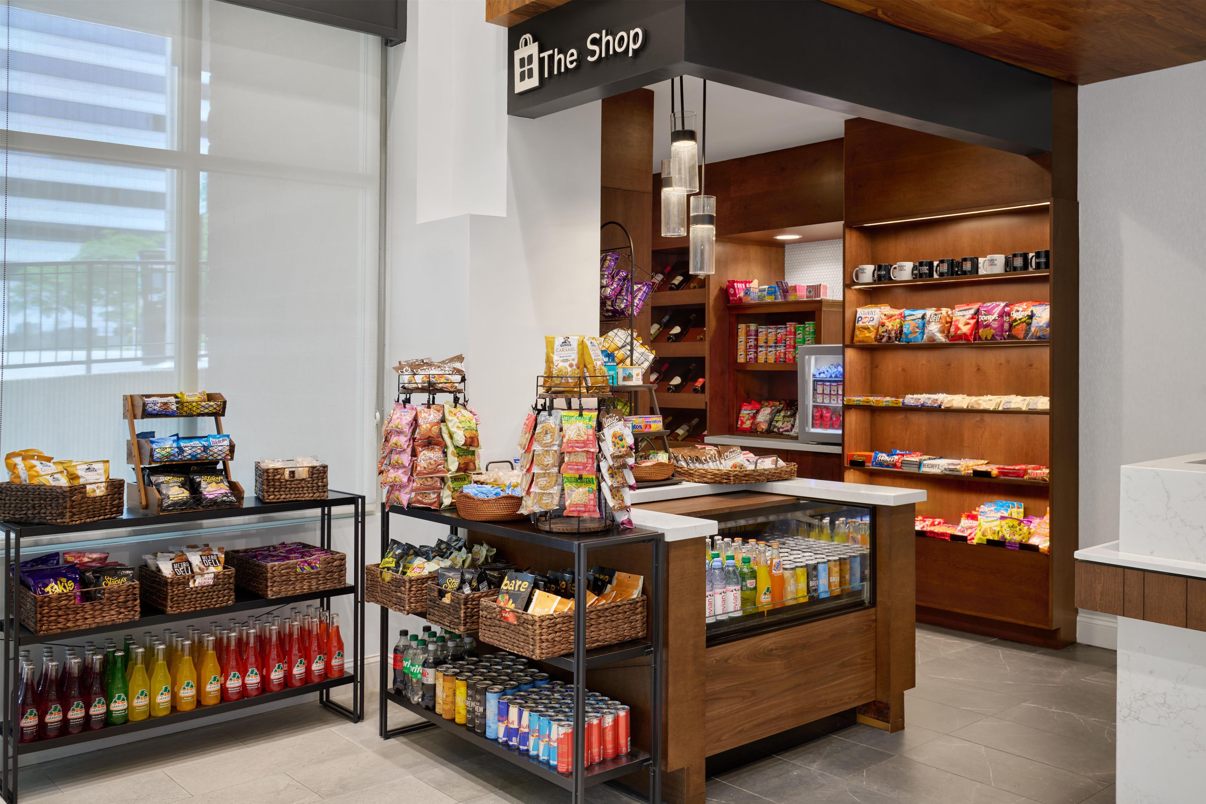 A store with shelves stocked with snacks, beverages, and a display case with bottled drinks.