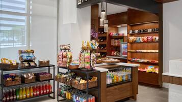 A store with shelves stocked with snacks, beverages, and a display case with bottled drinks.