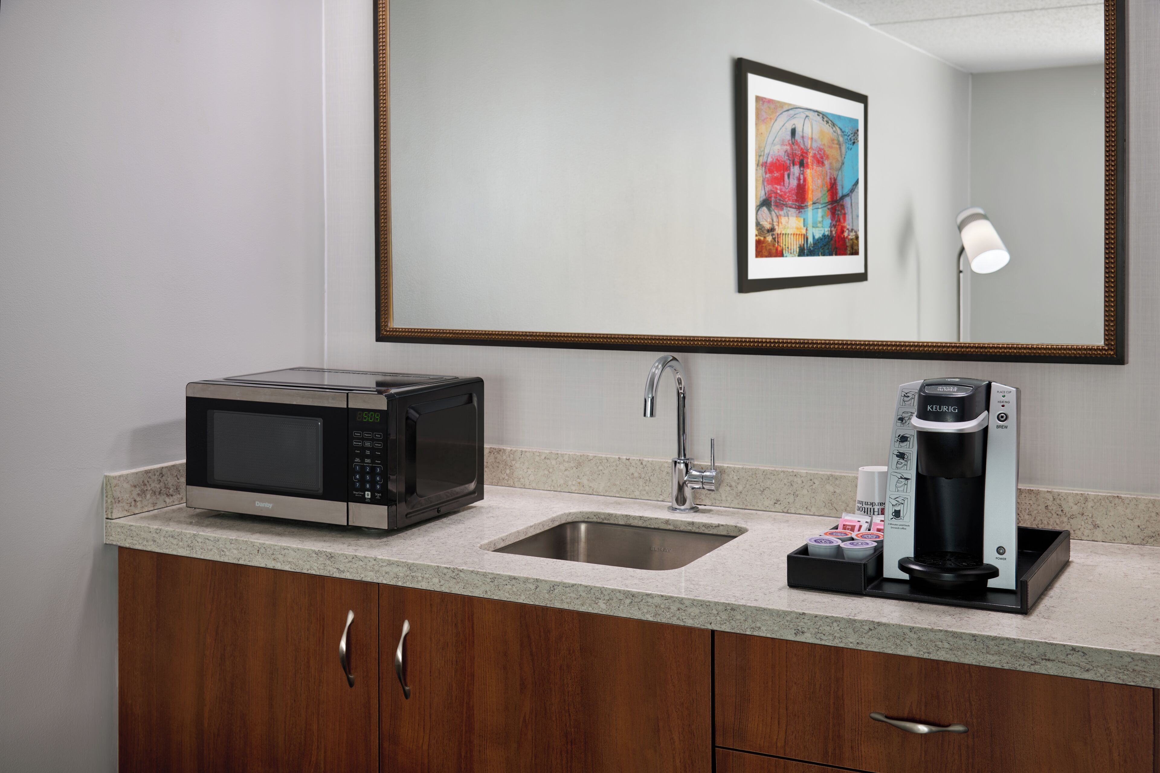 A modern kitchen with a microwave, coffee maker, and sink.