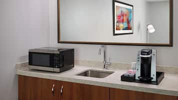 A modern kitchen with a microwave, coffee maker, and sink.