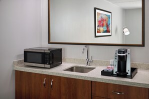 Una cocina moderna con microondas, cafetera y lavamanos.
