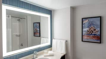 Une salle de bain avec un grand miroir, un lavabo, des toilettes et un tableau encadré au mur.