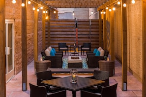An outdoor patio with wicker furniture, a table, and string lights. - Hilton Garden Inn Arlington/Courthouse Plaza (Arlington)