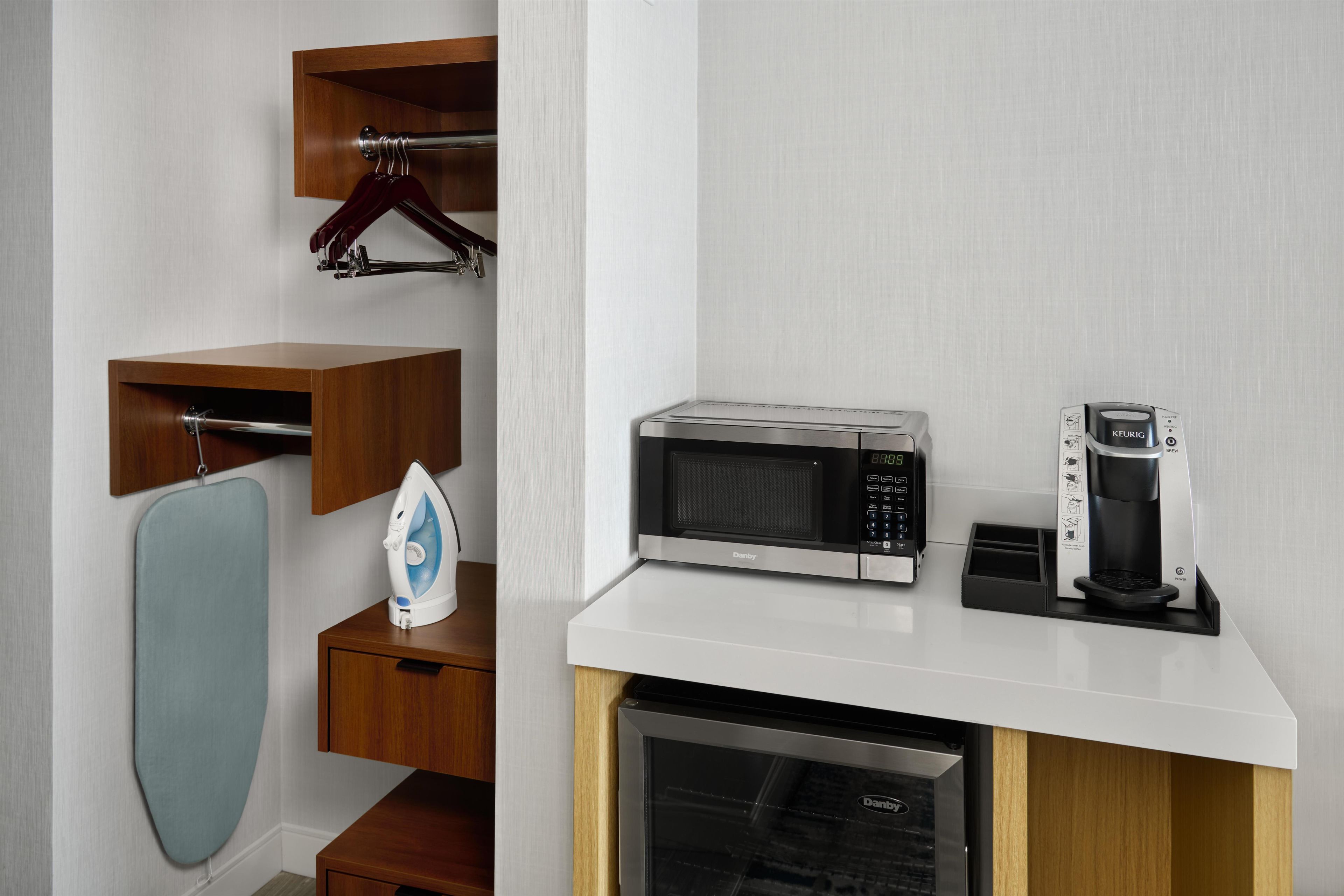A kitchen with a microwave, coffee maker, and an iron on the countertop.