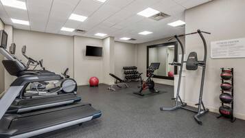 A fitness center with treadmills, a stationary bike, a rowing machine, and a wall-mounted TV.