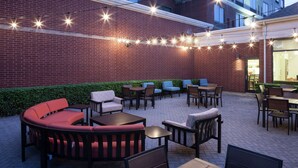 An outdoor patio with seating arrangements, including sofas and tables, and string lights.