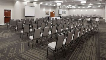 A conference room with rows of chairs, a projector screen, and a podium.