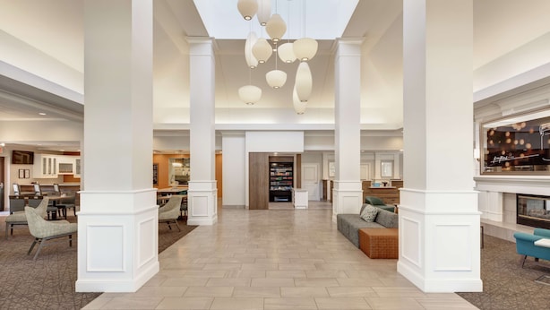 A spacious hotel lobby with high ceilings, a central seating area, and a modern chandelier.