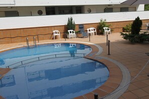 Una piscina al aire libre, sillones reclinables de piscina