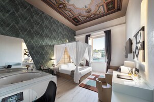 Una camera d'albergo moderna con un letto grande, un'area salotto separata, una vasca da bagno e vista sulla città.