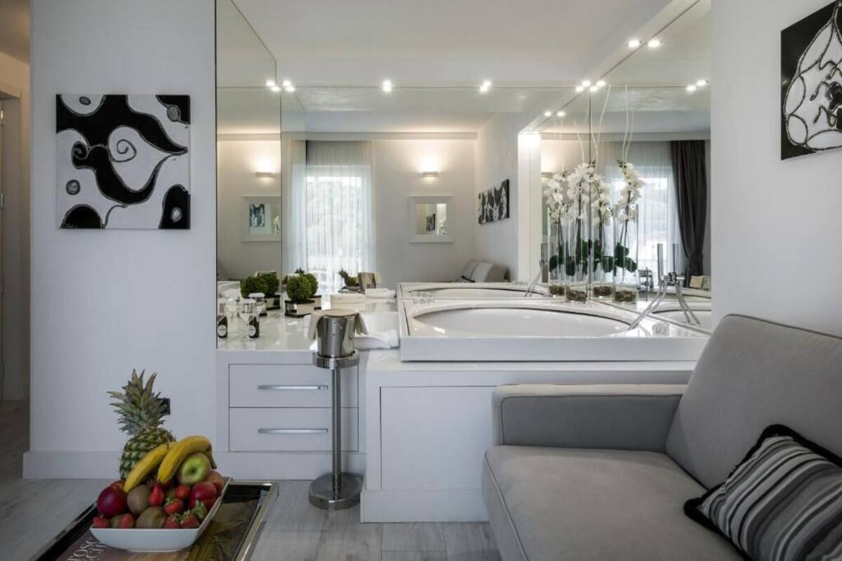 A modern bathroom with a large mirror, white cabinetry, and a fruit bowl on the counter.