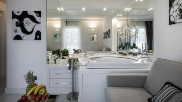 A modern bathroom with a large mirror, white cabinetry, and a fruit bowl on the counter.