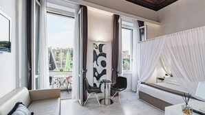 A modern hotel room with a large bed, a sitting area with a table and chairs, and a balcony with a view of the city. - LHP Hotel River & SPA (Florence)