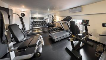 A gym with cardio machines, dumbbells, and a mirror.