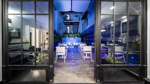A modern hotel lobby with a central seating area, a staircase, and a view of the outdoor terrace. - LHP Hotel River & SPA (Florence)