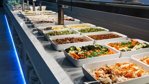 Un bufé con diversas opciones de comida, incluyendo ensaladas, carnes y verduras.