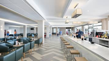 Un restaurant moderne doté d’un long comptoir, de tabourets de bar et d’un espace bar avec un présentoir à bouteilles.