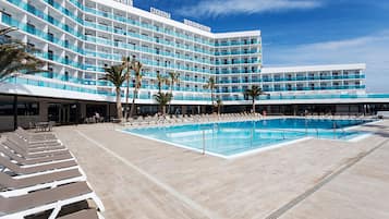 Un hotel con varias plantas, piscina y tumbonas.