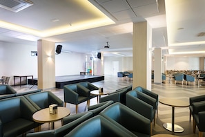 A spacious indoor area with seating arrangements, a stage, and a projection screen. - Hotel Best Sabinal (Roquetas de Mar)