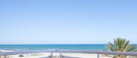 A balcony with a view of a beach and ocean.