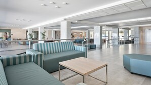 Un vestíbulo amplio con una zona de estar grande, una recepción y una escalera que sube a los pisos superiores.