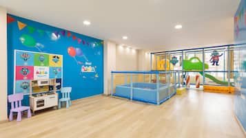 A children's play area with a blue wall, playpen, and colorful decorations.