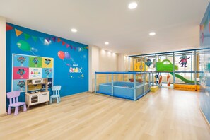 Zona infantil con pared azul, parque infantil y decoraciones coloridas.