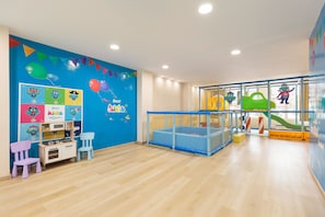 A children's play area with a blue wall, playpen, and colorful decorations.