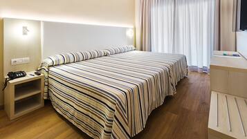 Ett hotellrum med en stor säng, sängbord, ett skrivbord och en tv.