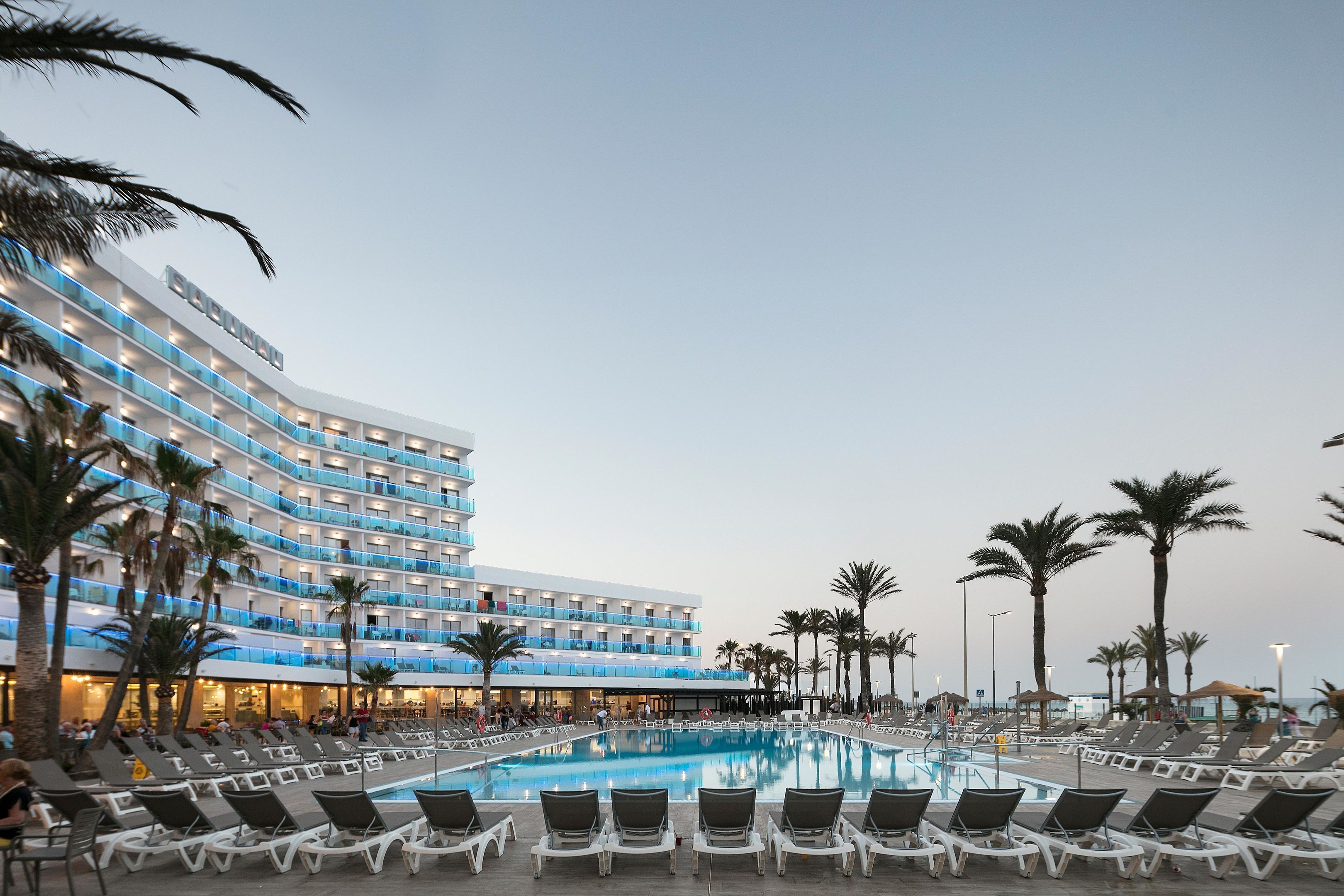 Ein Hotel mit großem Pool, mehreren Balkonen und Palmen.