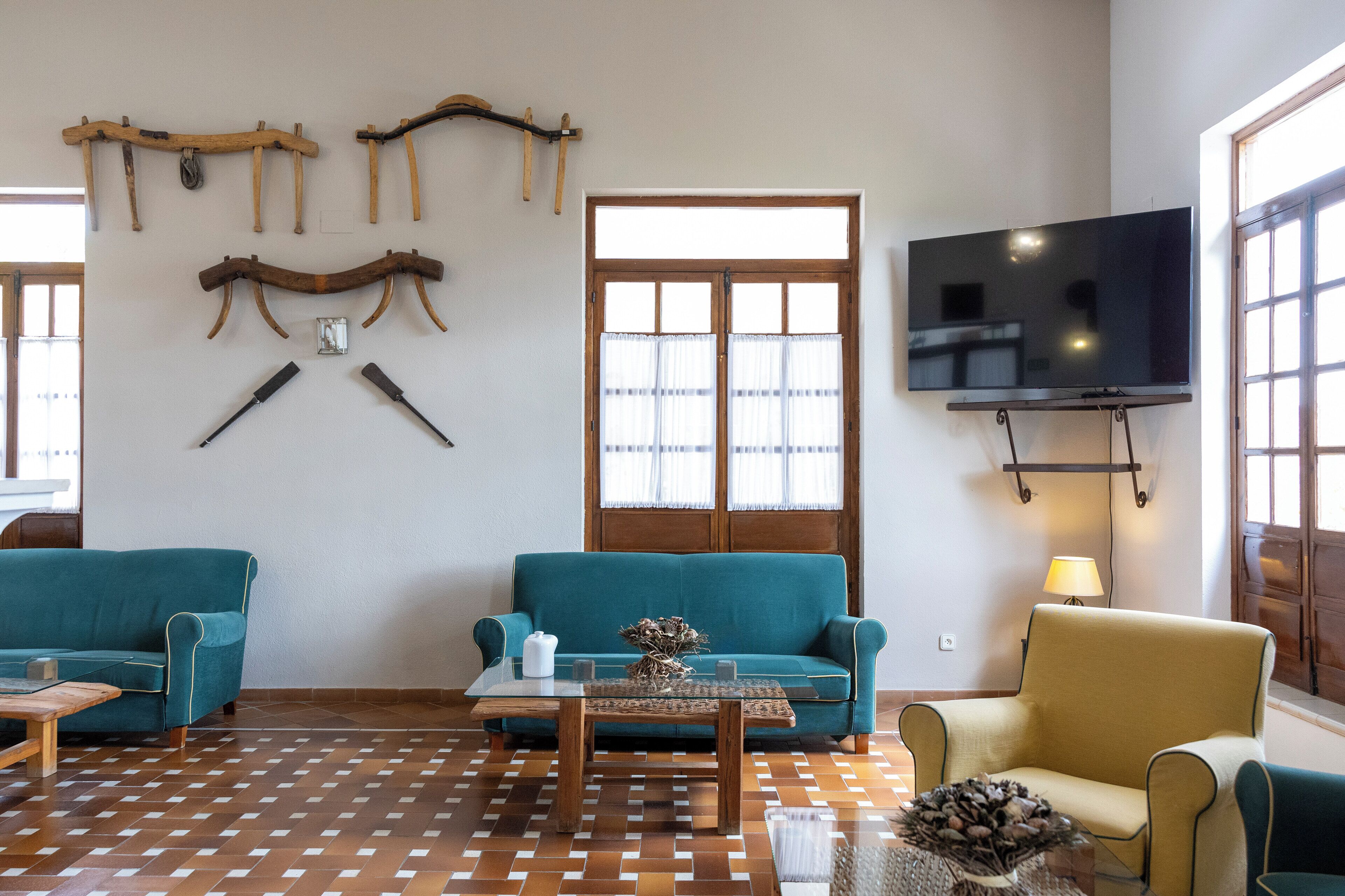 Un salon avec deux canapés, une table basse, un téléviseur fixé au mur et un sol à motifs.