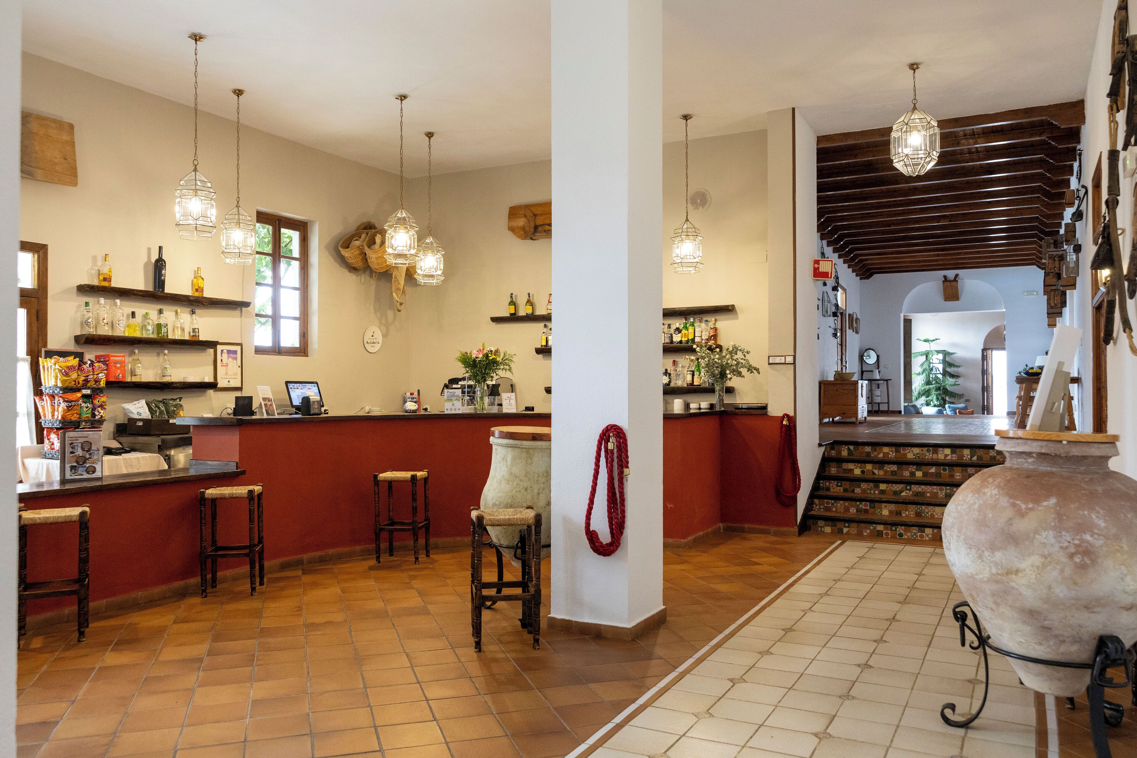 A kitchen with a red countertop, hanging lights, and a large pot on wheels.